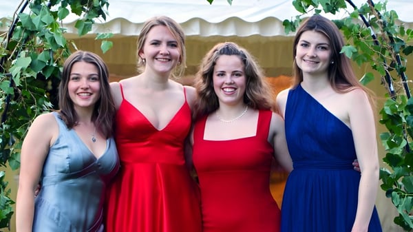 Cuatro alumnas de la Headington School posan juntas frente a un fondo verde.
