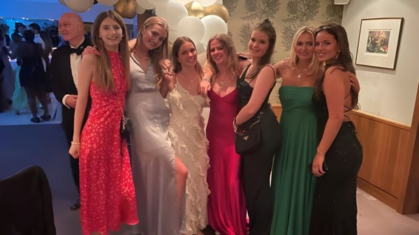 Un grupo de alumnas de la Heathfield School en Ascot posan vestidas de fiesta en una celebración con globos de fondo.