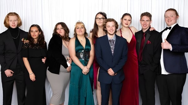Un grupo de personas en ropa formal posan juntos frente a un fondo blanco en el Heretaunga College.