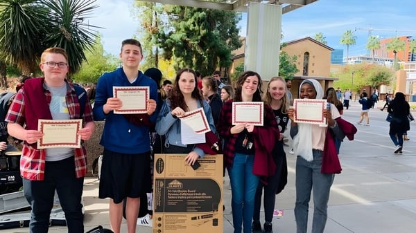 Estudiantes del Higley Unified School District sostienen certificados en el exterior.