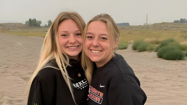Dos estudiantes sonrientes están en el paisaje desértico con calles y arbustos en el terreno de la Hillcrest High School.