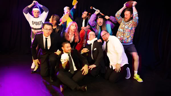 Un grupo de estudiantes está en el escenario del Hobart College frente a coloridas luces de escenario.