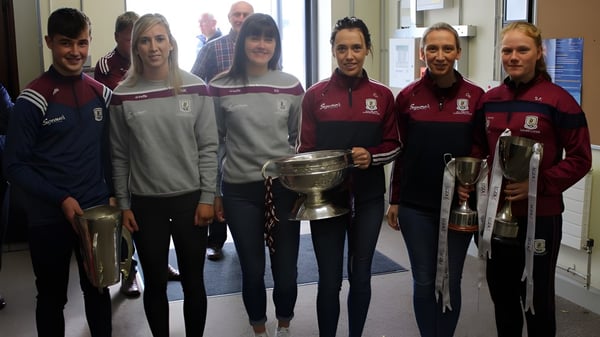 Un grupo de estudiantes en uniformes uniformes sostiene un trofeo en el pasillo del Holy Rosary College.