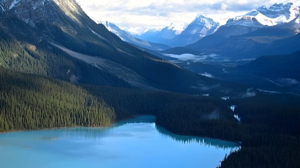 Un lago turquesa rodeado de montañas nevadas y bosques de coníferas en el terreno de la Holy Trinity High School.
