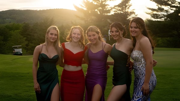 Un grupo de cinco jóvenes mujeres está de pie en un prado frente a una montaña boscosa en el terreno de la Hoosac School.