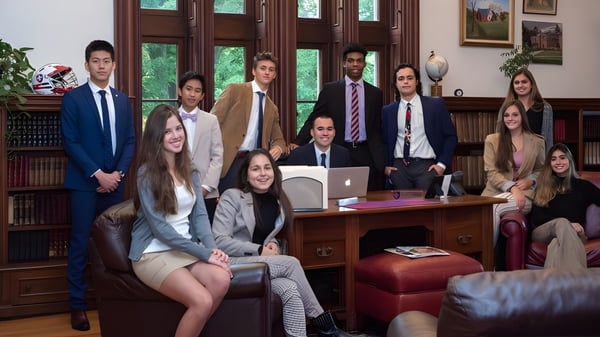 Un grupo de jóvenes profesionales trabaja juntos en una oficina revestida de madera de la Hoosac School.