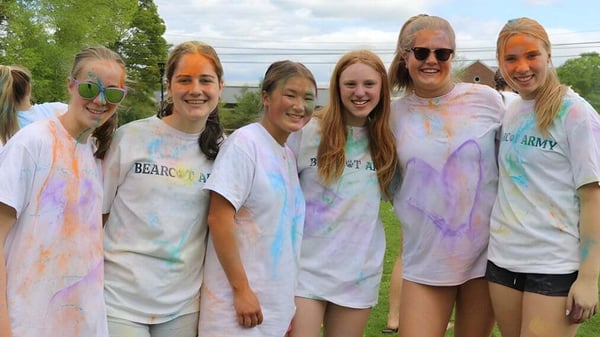 Un grupo de estudiantes de The Hotchkiss School posan afuera cubiertos de colorido frente a un fondo verde.