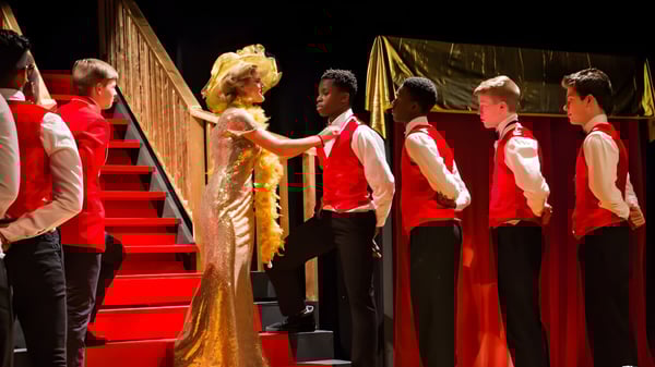 Un grupo de estudiantes de la Houghton Academy lleva vestimentas festivas en un escenario durante una ceremonia de graduación.