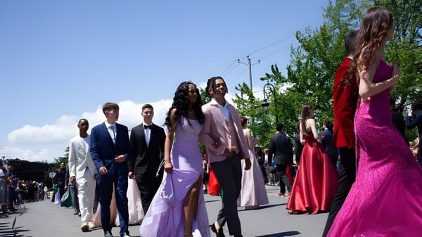 Estudiantes de la Howard S. Billings High School en ropa formal caminando por un camino rodeado de verde.