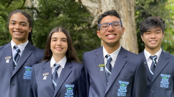 Cuatro estudiantes de la Hunters Hill High School están juntos en un entorno natural con árboles al fondo.
