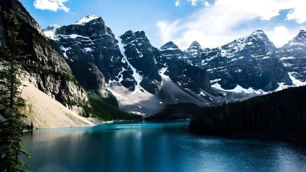 Un lago de montaña color turquesa rodeado de cumbres nevadas y paisaje verde en el terreno de la Huntsville School.