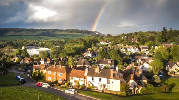 Un paisaje pintoresco con un arco iris sobre un pueblo en el terreno de Hurtwood House.