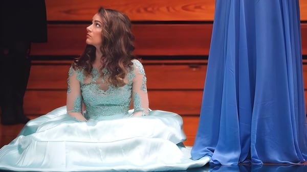 Una estudiante de la Immaculate Heart Central School está frente a una cortina azul.