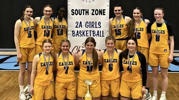 Estudiantes de la Immanuel Christian Secondary School posan juntas frente al banner del South Zone 2A Girls Basketball.