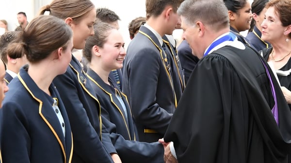 Un grupo de estudiantes en vestimenta de graduación está reunido en un evento ceremonial en el Immanuel College.