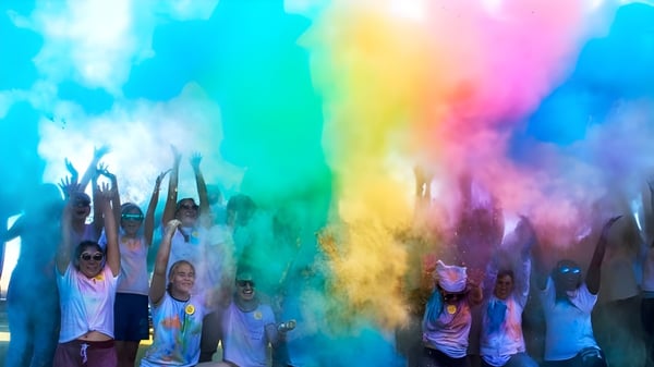 Estudiantes de la Indian River Charter High School celebran con polvo de colores en un evento festivo.