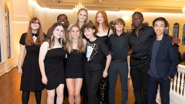Un grupo de estudiantes de la Indian Springs School posan en un espacio formal con detalles arquitectónicos decorativos.