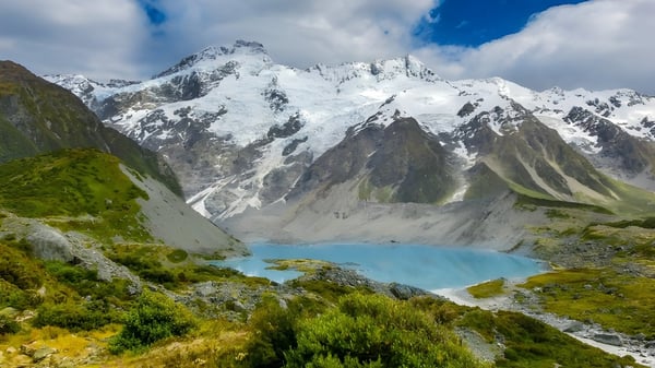 Un paisaje idílico con montañas nevadas y un lago turquesa frente a vegetación verde en los alrededores de Inglewood High School.
