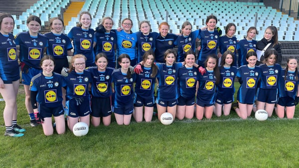 Un grupo de jóvenes futbolistas posa juntos en el campo del Inver College frente a una estructura similar a un estadio.