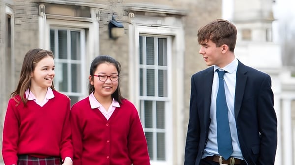 Tres estudiantes de Ipswich High School están frente a un edificio con grandes ventanas y están conversando.