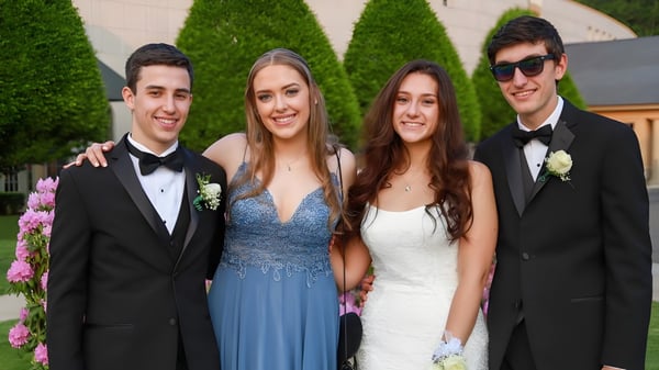 Cuatro personas en ropa formal posan juntas frente a un fondo verde en el terreno de la Ipswich School.