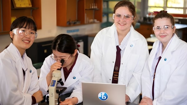 Cuatro mujeres con bata blanca están juntas en un laboratorio de la Ipswich State High School.
