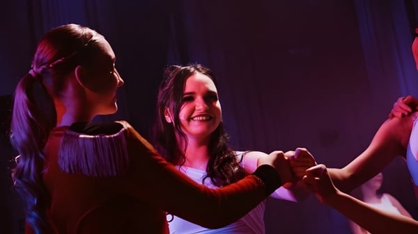 Dos alumnas bailan juntas en el escenario del Itchen Sixth Form College bajo luces de escenario de colores.