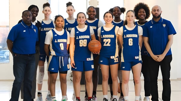 Un grupo de estudiantes de la J. Addison School está en camisetas de baloncesto azules y blancas en un gimnasio.