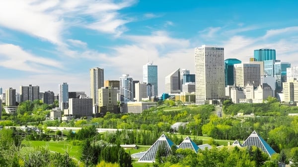 Una escena urbana vibrante con altos rascacielos y mucho verde bajo un cielo azul cerca de la J. Percy Page High School.