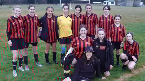 Un equipo de jóvenes futbolistas está junto en el campo deportivo del James Hargest College frente a la portería.