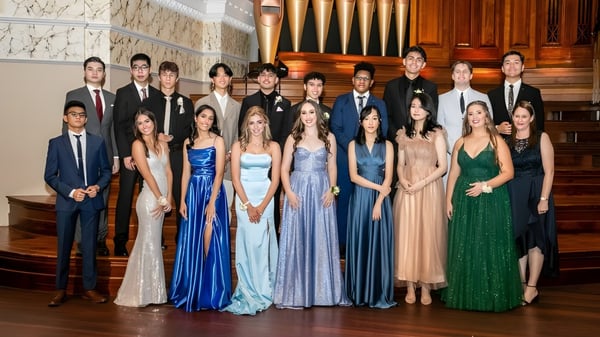 Un grupo de personas vestidas formalmente está de pie frente a un gran órgano en el lujoso interior del James Hargest College.