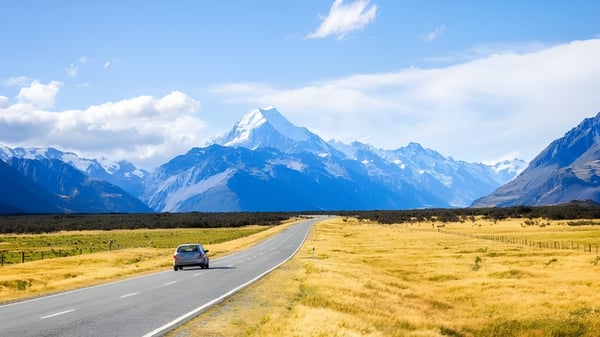 Un camino sinuoso conduce a través de una pradera dorada hacia montañas cubiertas de nieve cerca del James Hargest College.