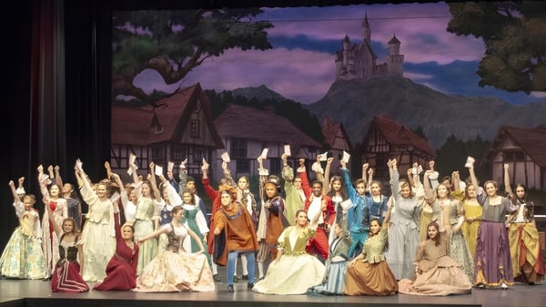 Estudiantes de la James M. Hill Memorial High School están frente a una escena medieval de castillo y pueblo.