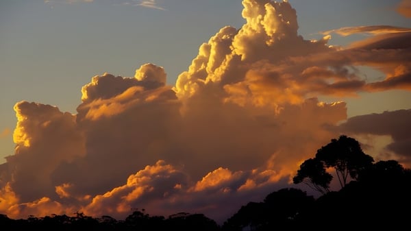 Un cielo dramático con nubes brillantes doradas sobre una silueta se puede ver sobre el terreno de la James Nash State High School.