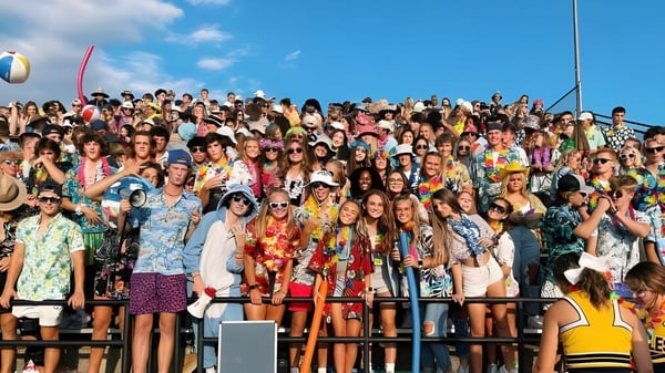 Un gran grupo de personas se reúne afuera bajo el cielo despejado en el terreno de la Jenison High School.