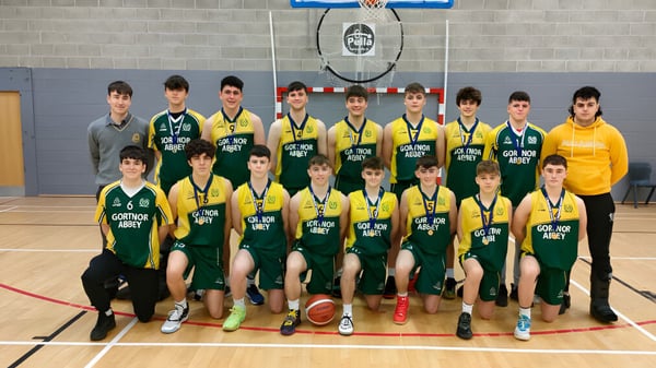 Un grupo de estudiantes de la Jesus and Mary Secondary School posan en el gimnasio frente a una canasta de baloncesto.
