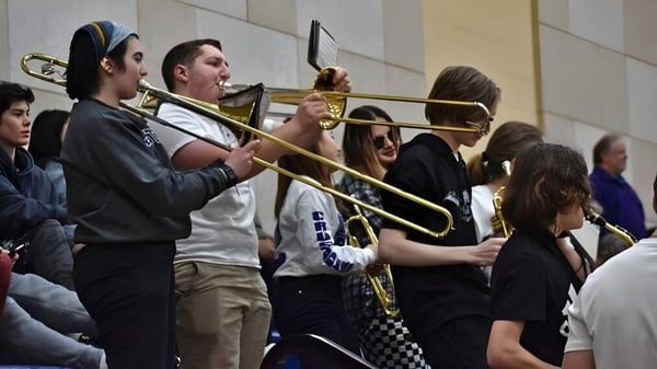Un grupo de estudiantes de la John Bapst Memorial High School se reúne con instrumentos musicales en el pasillo.