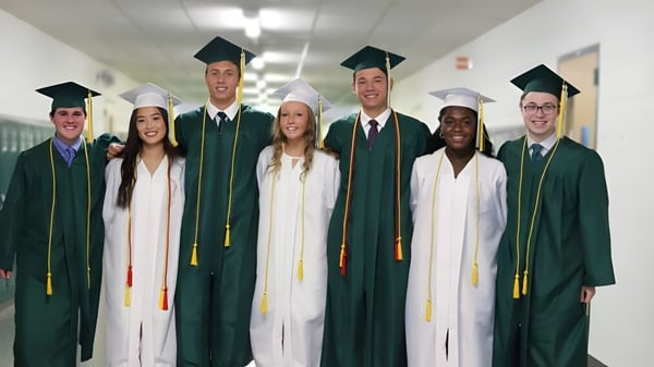 Un grupo de graduados con togas verde y blanca está en el pasillo del John F. Ross Collegiate Vocational Institute.