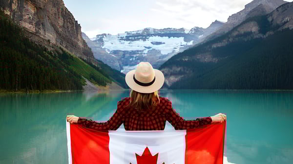 Una persona está frente a un lago turquesa con montañas nevadas en el terreno de la John McCrae Secondary School.