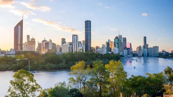 Vista de una ciudad vibrante con rascacielos y áreas verdes al atardecer cerca del John Paul College.