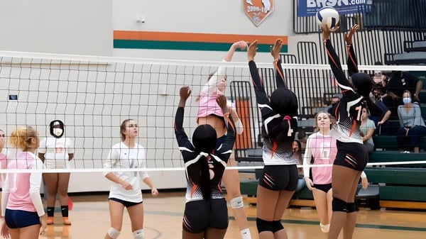 Un grupo de jugadoras de voleibol de la Jones High School compite en un torneo en la cancha.