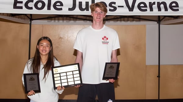 Dos estudiantes de la Jules Verne school Vancouver sostienen premios frente al edificio escolar.