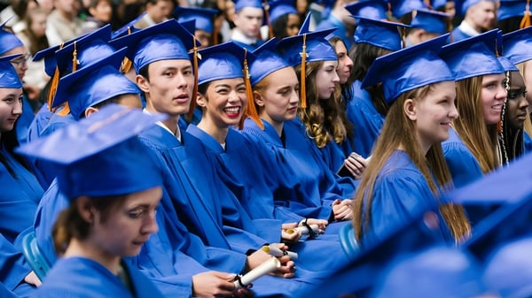 Un gran grupo de graduados de la Jules Verne school Vancouver lleva vestimenta de graduación azul y está juntos.