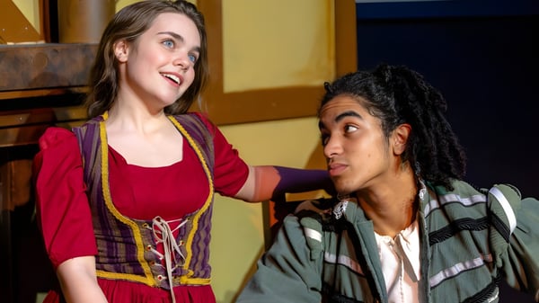 Dos estudiantes de la Justin Siena High School conversan y sonríen en una habitación con paredes de madera.