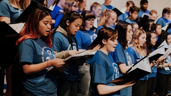 Estudiantes de la J.V. Humphries Secondary School están en camisas azules y cantan juntos en el coro.
