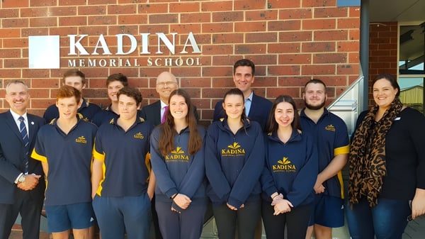 Estudiantes y personal de la Kadina Memorial School posan frente al edificio escolar en uniformes azules con el logo de la escuela.