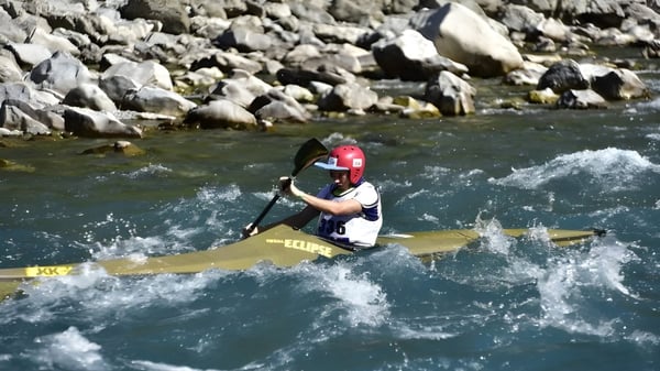 Un estudiante de la Kaiapoi High School navega en un kayak amarillo a través de las corrientes de aguas bravas en un entorno rocoso.