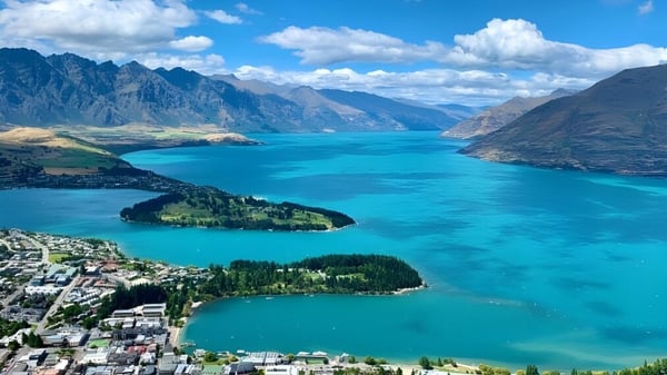 Toma aérea de un pintoresco lago con montañas y un paisaje verde cerca de Kaipara College.