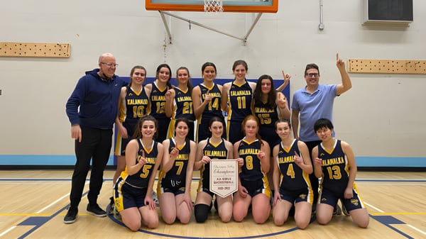 Un grupo de jóvenes jugadoras de baloncesto posan juntas en la cancha de la Kalamalka Secondary School.