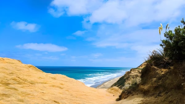 Un paisaje costero con acantilados escarpados y mar turquesa bajo un cielo azul sin relación con la Kamo High School.